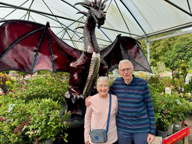 Mum and Dad standing in front of a large dragon sculpture at a garden centre